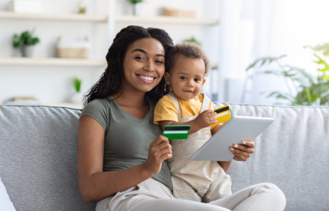 mujer con un bebé en brazos y una tarjeta de crédito